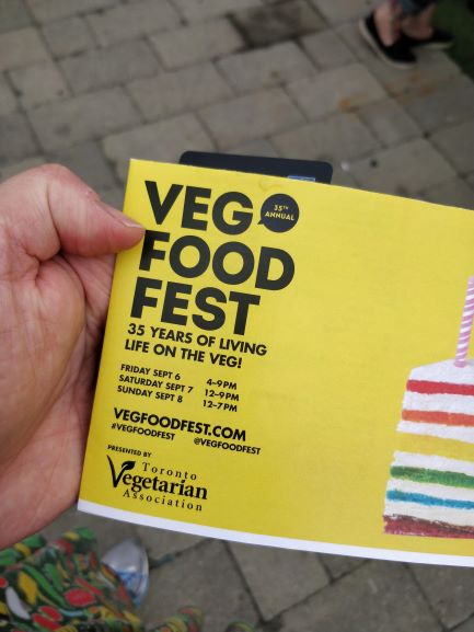 A picture of my hand holding a Veg Food Fest brochure.